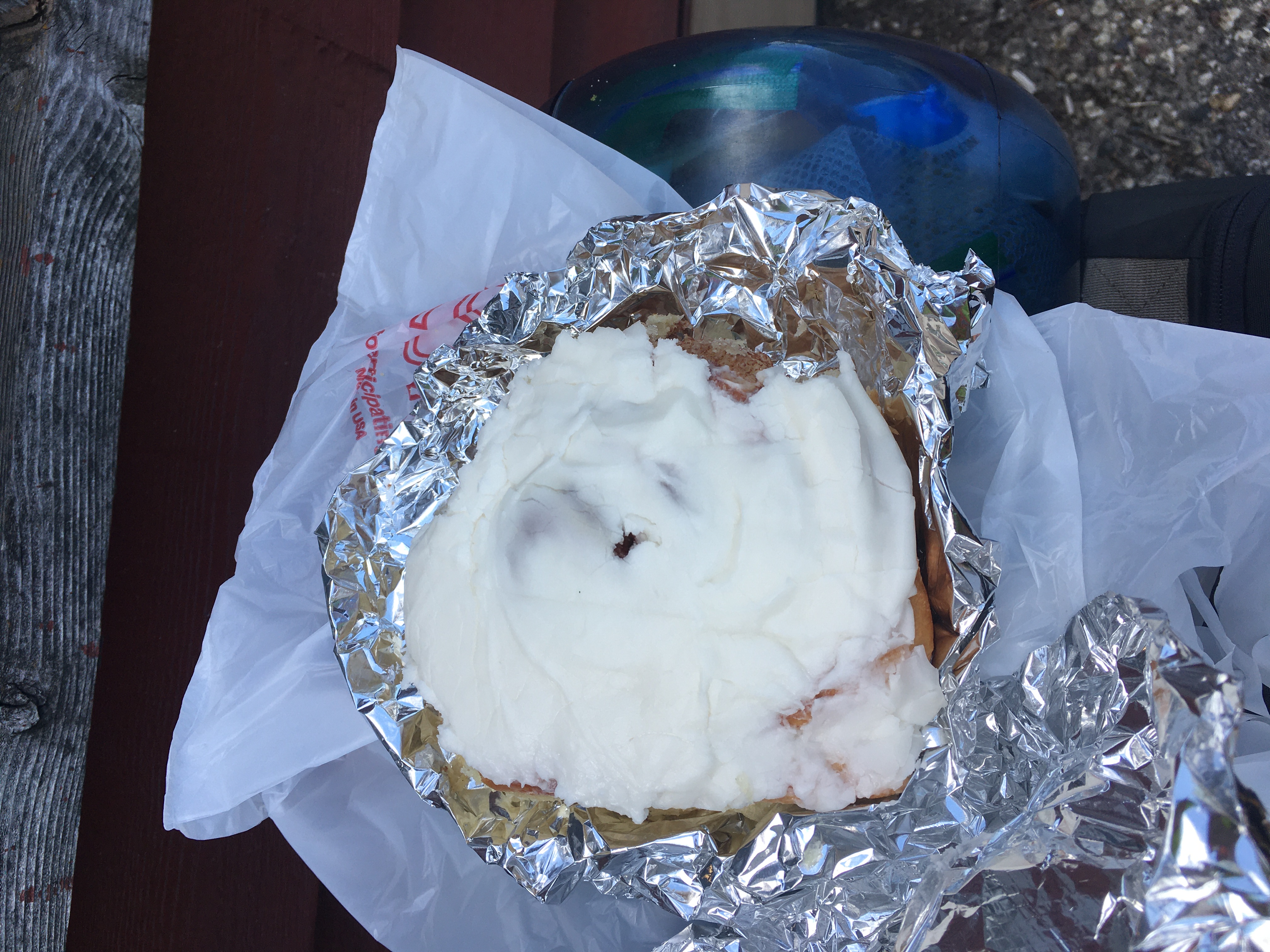 A very large cinnamon roll, wrapped in aluminum foil