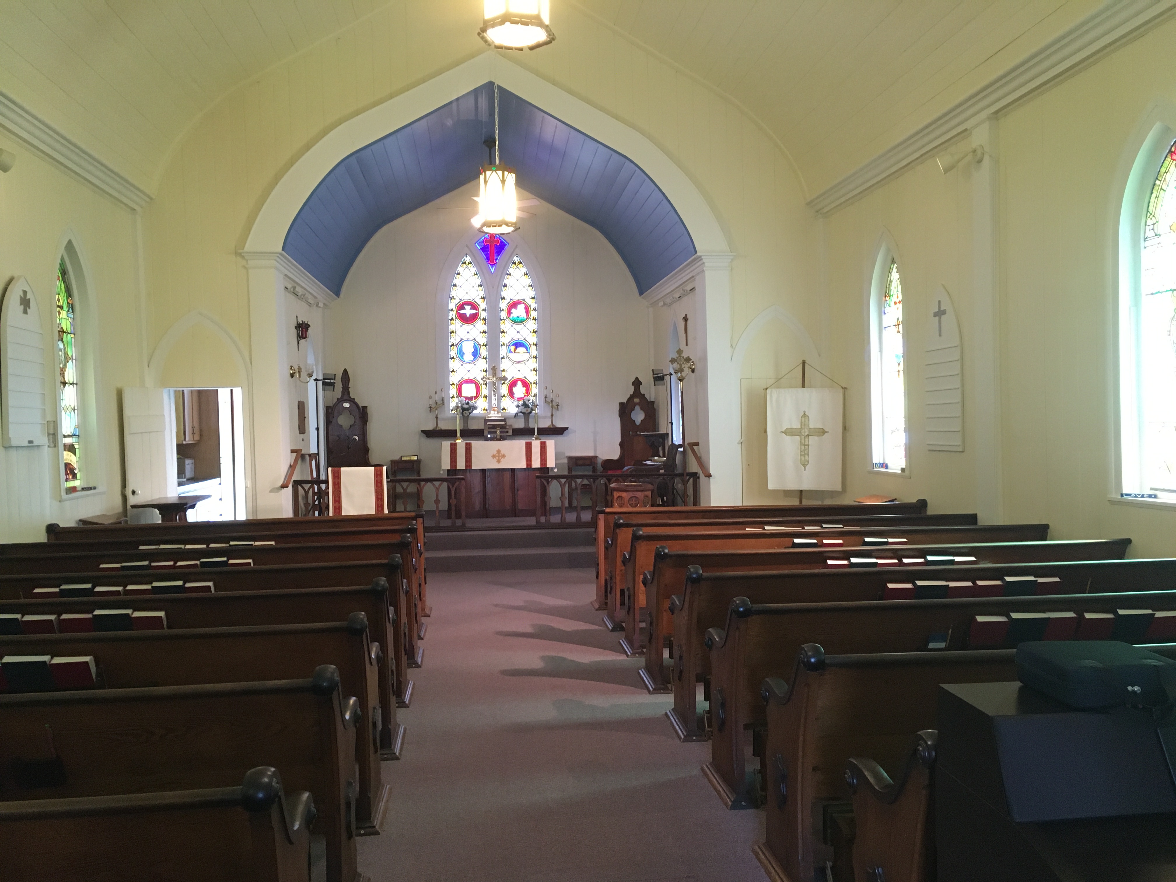 The interior of a small church – capacity about 80 people, with stained glass windows along the sides and straight ahead