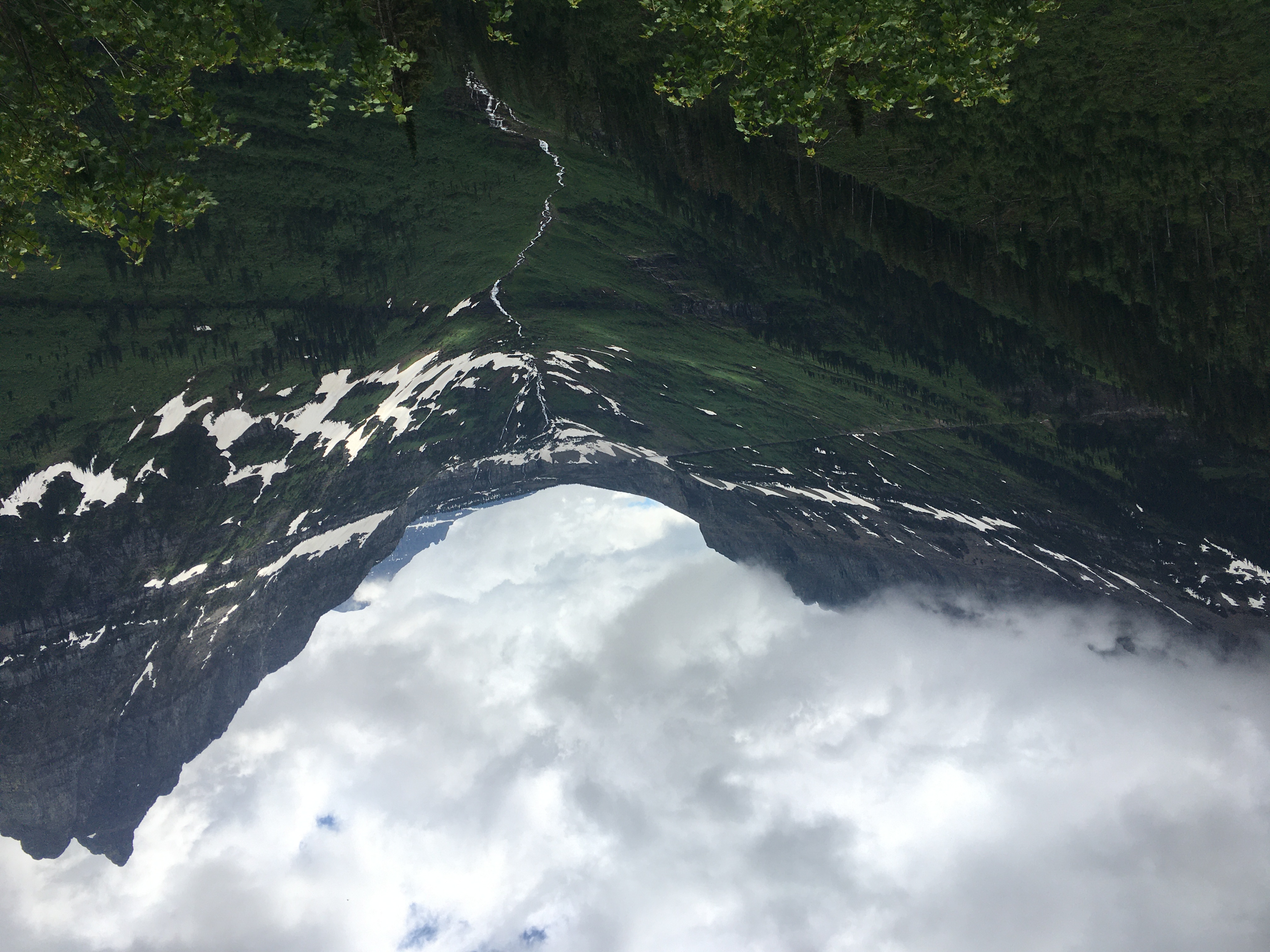 A classic U-shaped
glacially-carved valley where you can see the tree line – above it is bare
rock, below is trees and grasses. Snow is present on many of the slopes,
and a river meanders through the bottom of the valley. A peak on the right
is visible and sharp, while any peaks on the left are obscured by clouds.