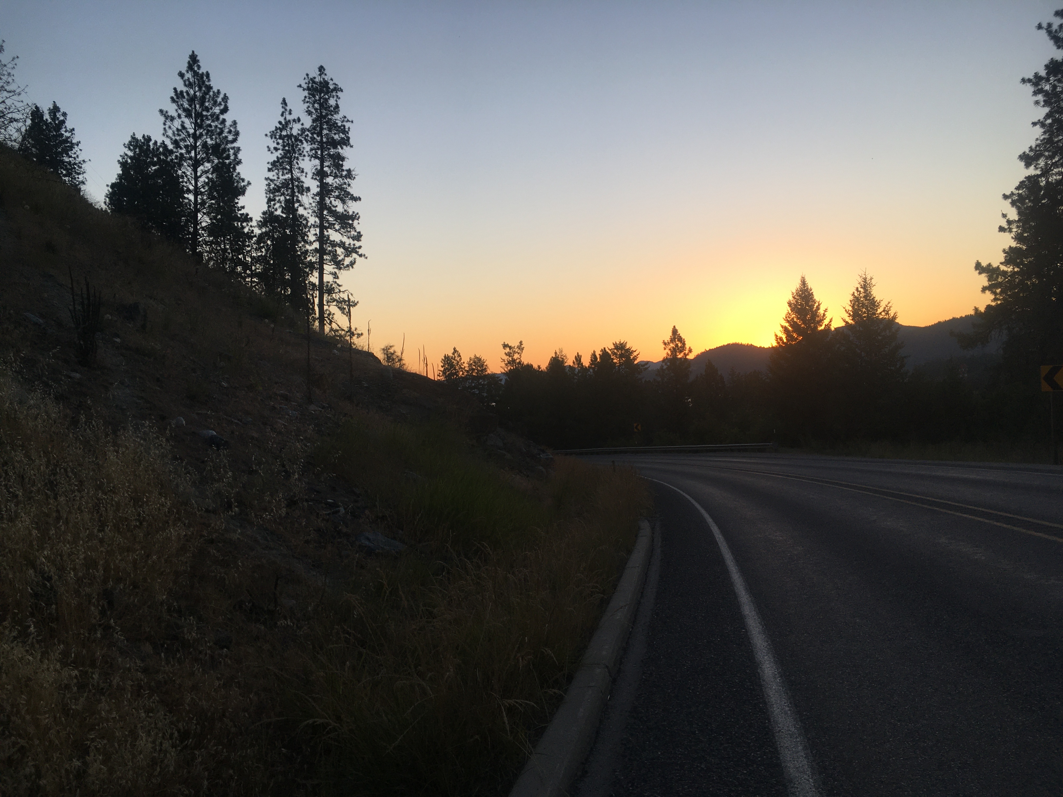 Early dawn shot with the sun
just below a hill in the distance, and yellow and orange sky. Trees and
hills are silhouetted