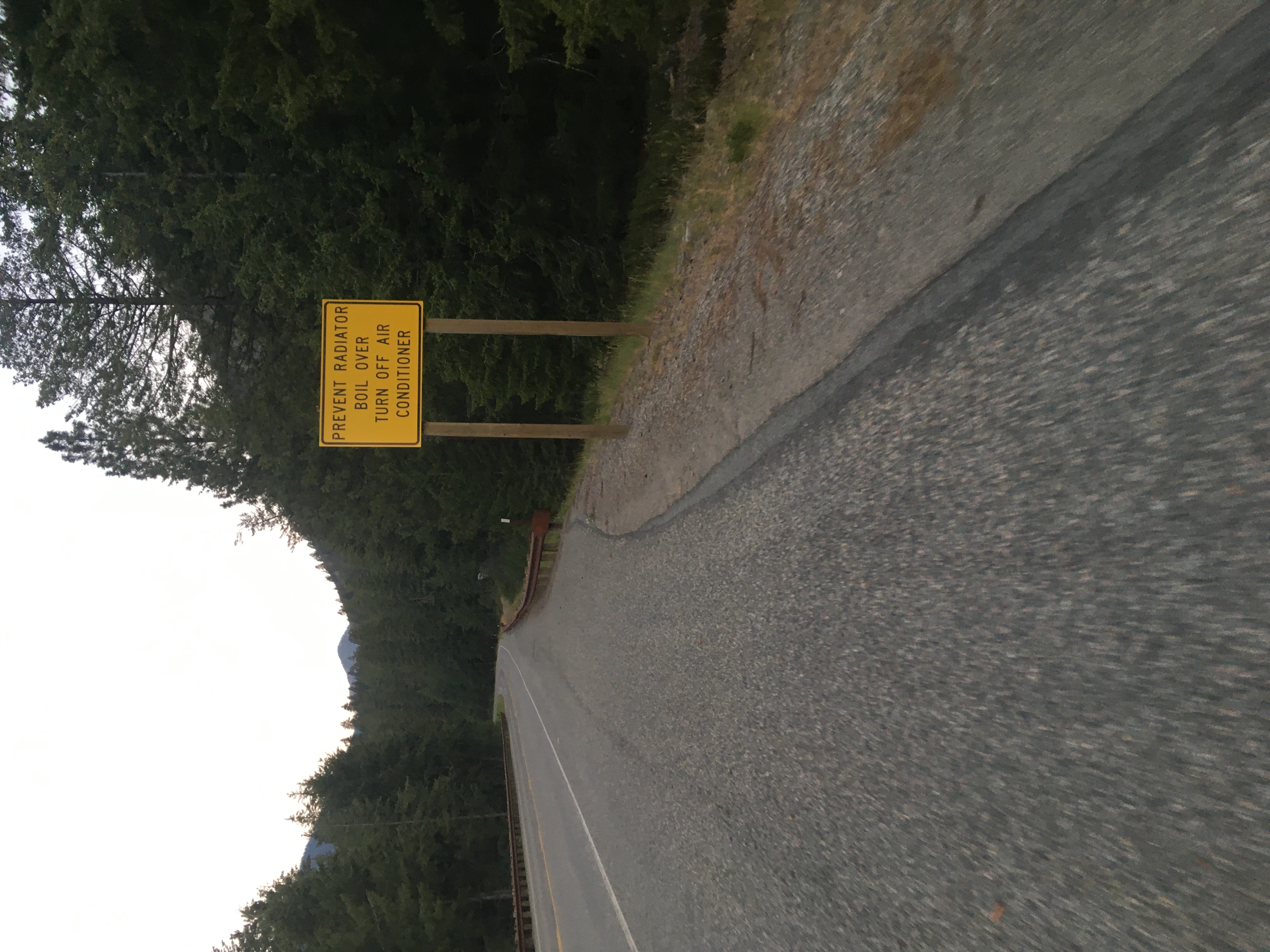 ominous yellow sign about
turning off a/c to prevent radiator boilover, with road and trees